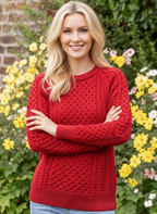 Woman wearing a red sweater standing in front of flowers and a brick wall