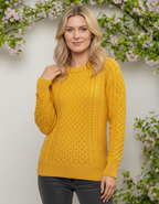 Woman wearing a yellow cable knit sweater with a floral background