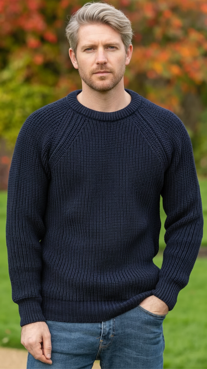 Man wearing a navy sweater standing outdoors with trees in the background
